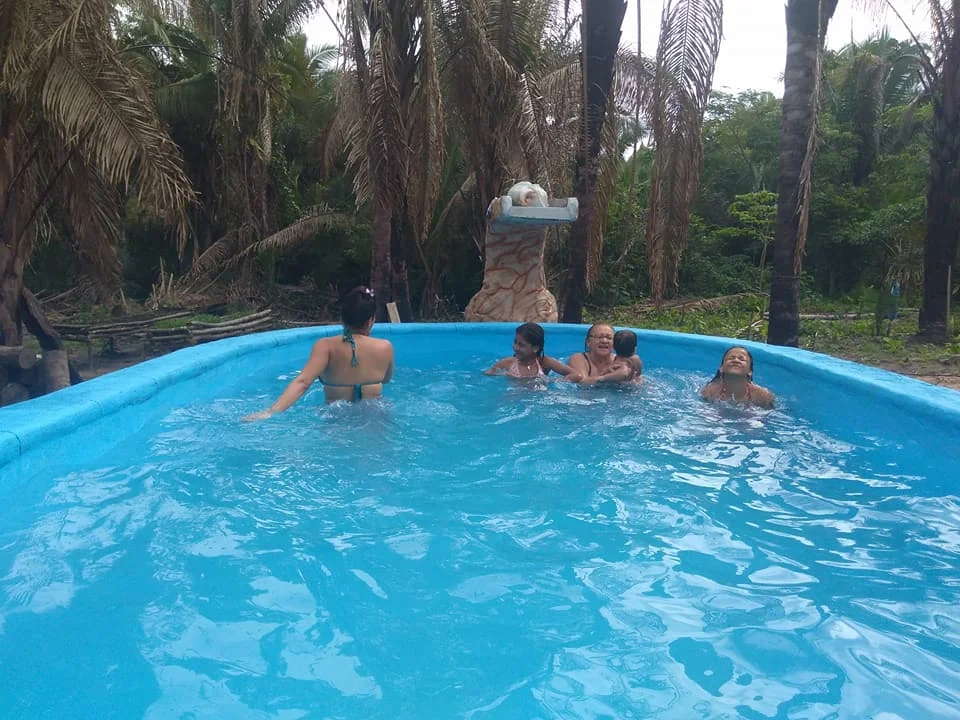 Piscina cheia com água azul, borda arredondada e pessoas na água